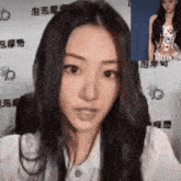 a woman with long black hair is sitting in front of a camera and looking at the camera .