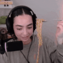 a woman wearing headphones is holding a spoon of noodles .