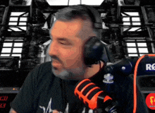 a man wearing headphones stands in front of a microphone with the letter r on the back
