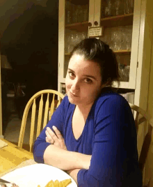 a woman in a blue shirt sits at a table