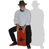a man wearing a hat sits on a cajon that says " tangosta " on it