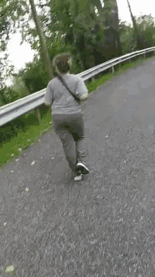 a woman is walking down a road with a shoulder bag .