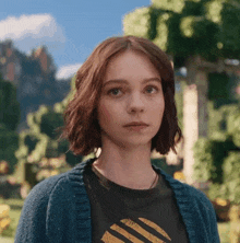 a young woman wearing a blue sweater and a black shirt with a yellow stripe on it
