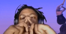 a man wearing headphones is making a funny face while holding his nose .