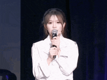 a girl in a white shirt is holding a microphone with the letter s on it