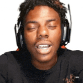 a man wearing headphones is making a funny face with his eyes closed .