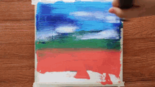 a person is painting a picture of a field with a blue sky in the background