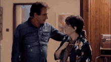 a man in a denim shirt is standing next to a woman