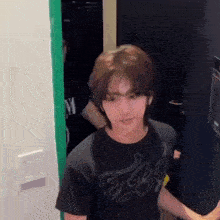 a young man in a black t-shirt is standing in a room .