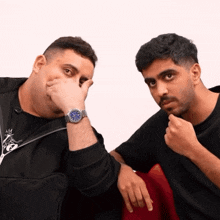 two men sitting next to each other one wearing a watch that says ' rolex ' on the face