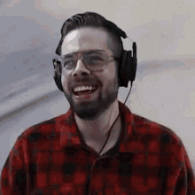 a man with a beard wearing headphones and glasses is smiling .