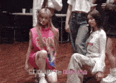 a girl in a pink shirt with the word s on it sits on the floor