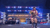 a woman in a wrestling ring with a sign that says " and new wwe women 's world champion "