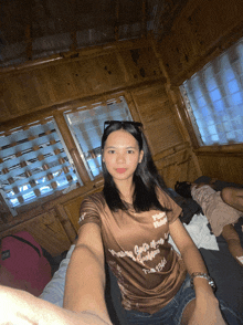 a woman taking a selfie in a wooden cabin wearing a shirt that says ' new york city ' on it