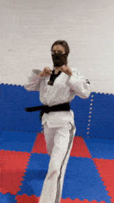 a woman in a karate uniform is wearing a black mask