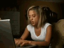 a woman is typing on a laptop in a dark room