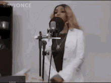 a woman is singing into a microphone while wearing a white jacket .