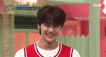 a young man wearing a red and white basketball jersey is smiling in front of a tvn logo