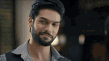 a man with a beard is making a funny face while looking at the camera .