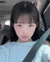 a girl wearing a headband is sitting in a car with a seat belt on