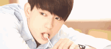 a young man is licking a lollipop in his mouth