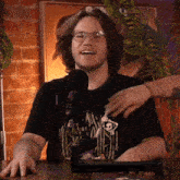 a man wearing a shirt that says ' nightmare before christmas ' is smiling in front of a microphone