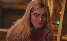 a close up of a blonde woman with long hair looking at the camera .