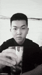 a black and white photo of a man holding a glass of water .