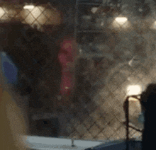 a blurry picture of a person standing in front of a window with a fence in the background .