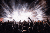 a crowd of people at a concert with their hands up