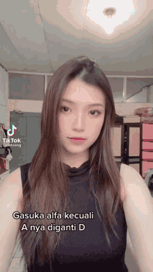 a girl with long hair is wearing a black tank top and has a tiktok account