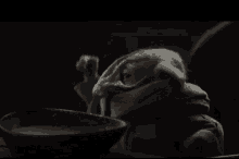 a close up of a baby yoda eating from a bowl .
