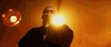 a man is singing into a microphone in front of a spotlight in a dark room .