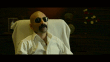 a bald man with a mustache wearing sunglasses and a white shirt