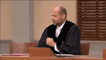 a man in a judge 's robe is speaking into a microphone in a courtroom