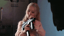 a woman is holding a gun in front of a sign that says mini k