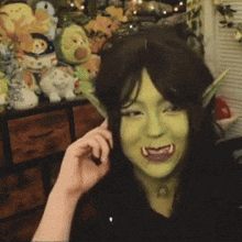 a woman with green paint on her face is talking on a cell phone