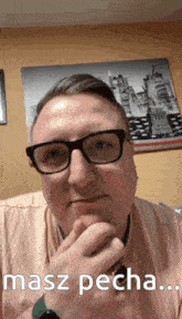 a man wearing glasses is sitting in front of a picture of the statue of liberty ..