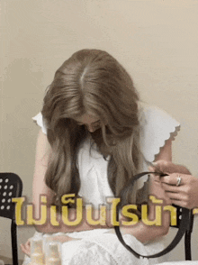 a woman in a white dress is looking at her hair in front of a sign that says ' ui ' on it