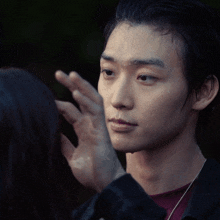 a close up of a person touching a man 's face with their hand