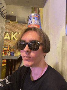 a man wearing sunglasses has a can on top of his head that says ' coca cola ' on it