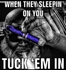 a man with a beard is smoking a blue cigar with a caption that says when they sleepin on you tuck em in