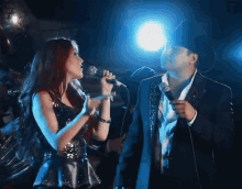 a woman singing into a microphone next to a man with a cowboy hat