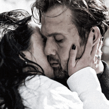 a black and white photo of a woman kissing a man on the forehead