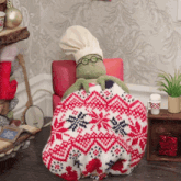 a stuffed animal wearing a chef 's hat and glasses is wrapped in a knitted blanket