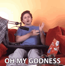 a man sitting on a couch with a bag of chips and the words oh my godness on the bottom