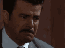 a man in a suit and tie is crying with his eyes closed