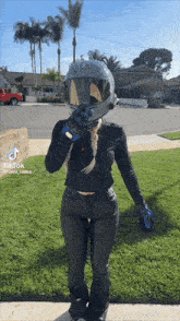 a woman wearing a motorcycle helmet and gloves is standing on a sidewalk