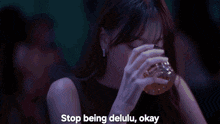 a person holding a glass with the words " stop being delulu okay " below it