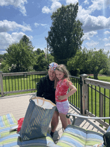 a man and a little girl on a deck with a bag